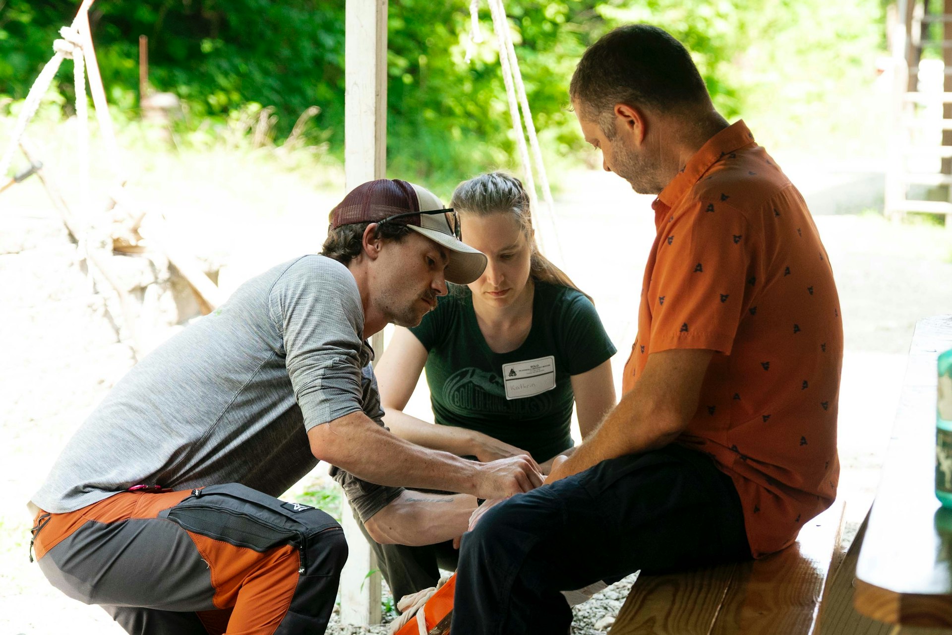 Three people gathered outdoors, looking down at something.